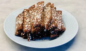 En hög med choklad snittar, toppade med pärlsocker, ligger på en ljusblå tallrik.