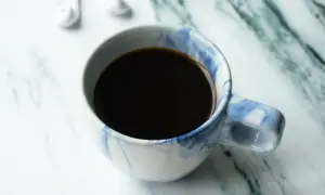 En kopp kaffe, perfekt för att njuta av ditt americano recept. Vita hörlurar ligger bredvid.