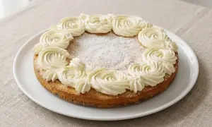 En glutenfri semmelkladdkaka med fluffig grädde runt kanten, pudrad med florsocker.