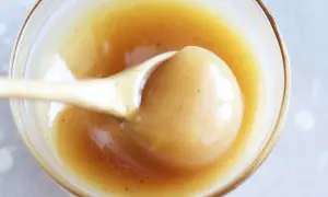 En sked lyfter krämig kolasås ur en skål. Perfekt för ditt kolasås recept!