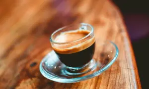En liten kopp espresso ristretto med krämig crema på ett träbord.