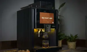 Svart kaffemaskin brygger en kopp kaffe, med texten "Tala om gott kaffe" på skärmen. Perfekt för dig som vill ha exakt rätt mängd gram kaffe per kopp.