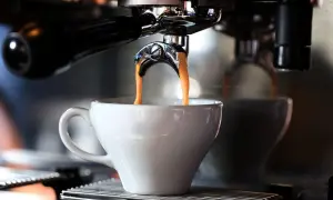 En liten espresso rinner ner i en vit kopp från en espressomaskin.