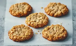 Fem gyllene, mjuka havrekakor ligger utspridda på bakplåtspapper. De ser perfekta ut att doppa i mjölk.