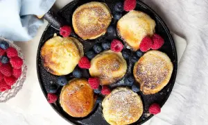 Små, gyllene krabbelurer i stekpanna, pudrade med florsocker och dekorerade med färska hallon och blåbär. Ett härligt recept för frukost eller fika.