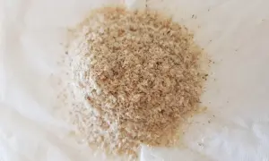 En hög med fiberhusk psyllium på vitt papper.