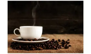 En vit kaffekopp med ånga stiger från den, omgiven av kaffebönor. En perfekt bild för att fundera på hur många skopor kaffe till 2 koppar.