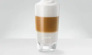 En perfekt lagerdelad latte macchiato i ett glas med Jura-logotyp.