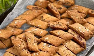 En hög med hembakade kolakakor med chokladbitar, strösslade med flingsalt. Perfekt för ett kolakakor recept!