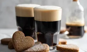 Två mörka kaffedrinkar med Cointreau och hjärtformade pepparkakor pudrade med florsocker.