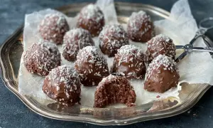 Chokladiga havrebollar, perfekta för ett snabbt havrebollar recept. Garnerade med kokosflingor på en silverbricka.