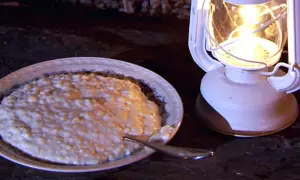 En skål med krämig risgrynspudding med bittermandel, belyst av en vit oljelampa.