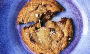 En chokladchipkaka, delad, med smält choklad som rinner ut. Strössel av flingsalt.