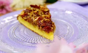 En bit glutenfri toscakaka med mandeltosca på en vacker glasfat.