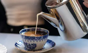Grädde hälls i en vacker blåvit kaffekopp. Kanske en del av svaret på vilket land dricker mest kaffe?