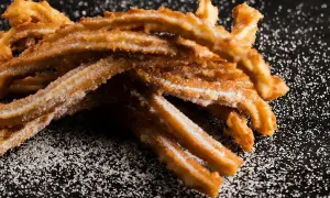 Krispiga churros, pudrade med socker, redo att avnjutas. Ett perfekt churros recept för hemmabruk.