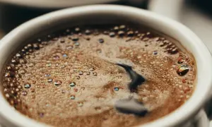 En vit kopp med bubbligt java kaffe. Skummet har regnbågsskimrande bubblor och en mörk virvel i mitten.