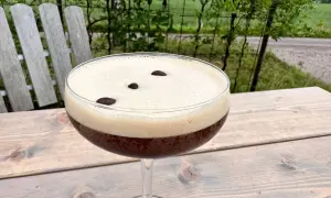 En härlig espresso martini med krämigt skum och tre kaffebönor, perfekt för en stunds avkoppling utomhus.