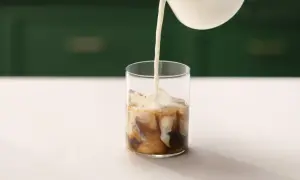 Mjölk hälls i ett glas med is och kaffe. Ett perfekt iskaffe recept för en varm dag.