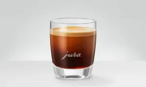 En perfekt dubbel espresso med gyllene crema i ett elegant glas med Jura-logotypen.
