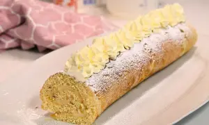En härlig semmelrulltårta glutenfri, pudrad med florsocker och toppad med grädde. Perfekt för fikat!