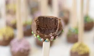 Chokladiga cake pops med färgglada strössel. En är uppäten och visar det saftiga inkråmet.