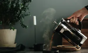 En hand häller upp ångande kaffe ur en presskanna. Perfekt presskaffe tid.