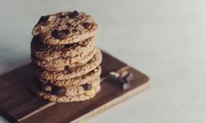En hög med glutenfria småkakor från Lailas, med chokladbitar och nötter, ligger på en träskärbräda.