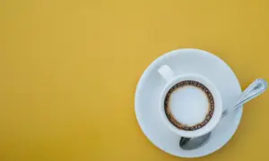 En kopp kaffe macchiato med skum och en ring av kaffe på en gul bakgrund. Perfekt för ett enkelt macchiato recept.