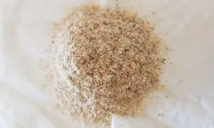En hög med ljusbrunt fiberhusk, som ser ut som små, tunna flingor, ligger på en vit yta.