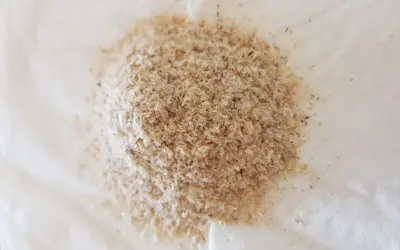 En hög med fiberhusk psyllium på vitt papper.