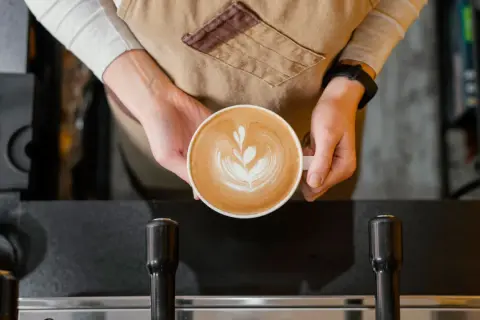 Barista håller en vacker latte med latte art. Undrar hur många koppar kaffe per paket Zoegas det blir?