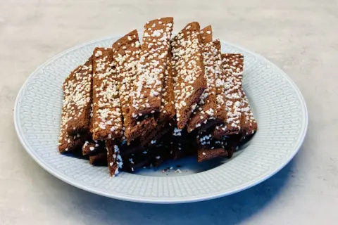 En hög med choklad snittar, toppade med pärlsocker, ligger på en ljusblå tallrik.