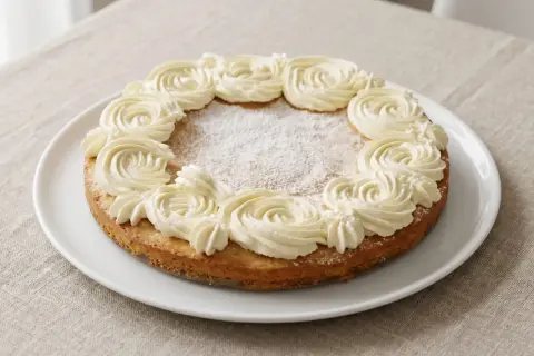 En glutenfri semmelkladdkaka med fluffig grädde runt kanten, pudrad med florsocker.