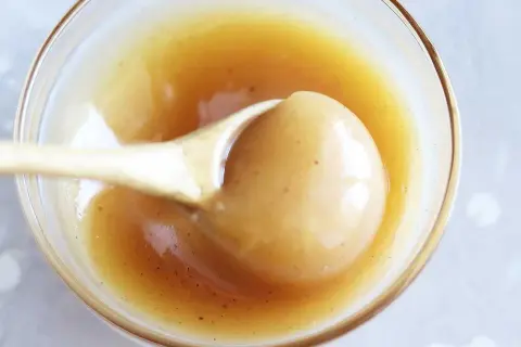 En sked lyfter krämig kolasås ur en skål. Perfekt för ditt kolasås recept!