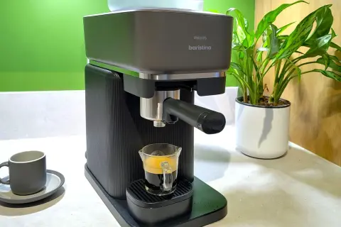 En Philips Baristina espressomaskin brygger en perfekt shot kaffe till espressomaskin. En grön vägg och en krukväxt i bakgrunden.