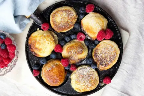 Små, gyllene krabbelurer i stekpanna, pudrade med florsocker och dekorerade med färska hallon och blåbär. Ett härligt recept för frukost eller fika.