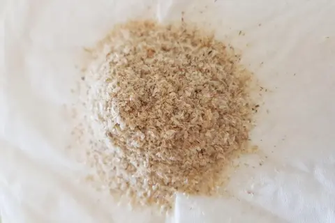 En hög med fiberhusk psyllium på vitt papper.
