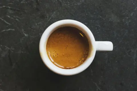 En vit kopp med en gyllene espresso, en perfekt start på dagen med äkta italienska kaffesorter.