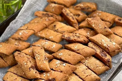 En hög med hembakade kolakakor med chokladbitar, strösslade med flingsalt. Perfekt för ett kolakakor recept!