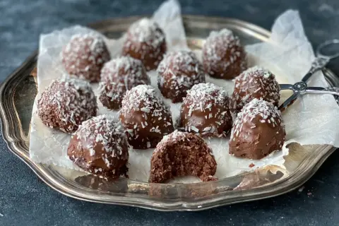 Chokladiga havrebollar, perfekta för ett snabbt havrebollar recept. Garnerade med kokosflingor på en silverbricka.