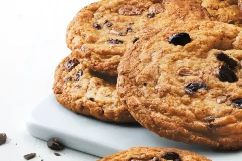En hög med gyllene, glutenfria chocolate chip cookies, perfekta för en fika.