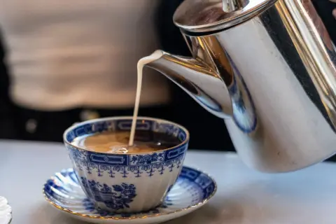 Grädde hälls i en vacker blåvit kaffekopp. Kanske en del av svaret på vilket land dricker mest kaffe?