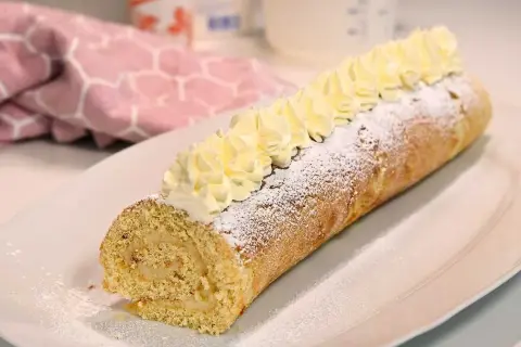 En härlig semmelrulltårta glutenfri, pudrad med florsocker och toppad med grädde. Perfekt för fikat!
