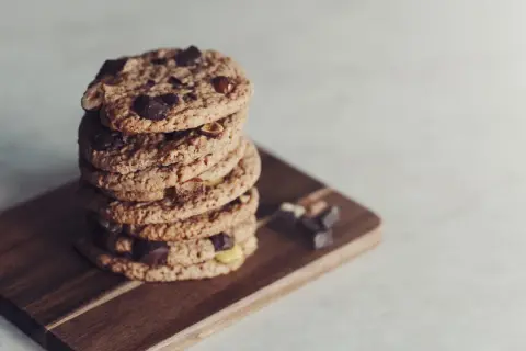 En hög med glutenfria småkakor från Lailas, med chokladbitar och nötter, ligger på en träskärbräda.