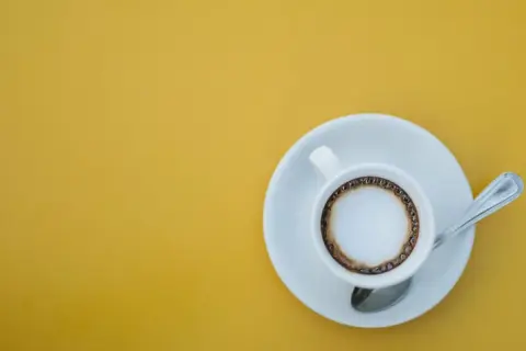 En kopp kaffe macchiato med skum och en ring av kaffe på en gul bakgrund. Perfekt för ett enkelt macchiato recept.