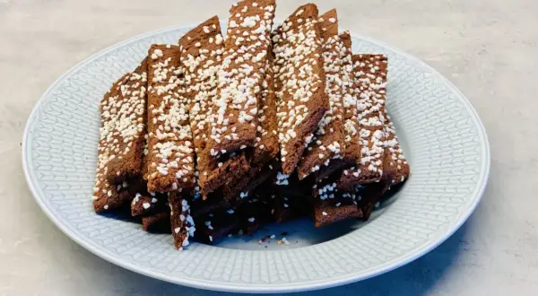 En hög med choklad snittar, toppade med pärlsocker, ligger på en ljusblå tallrik.
