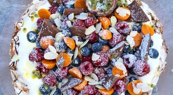 En vacker pavlova med bär, choklad och passionsfrukt. Ett perfekt pavlova recept för sommaren.