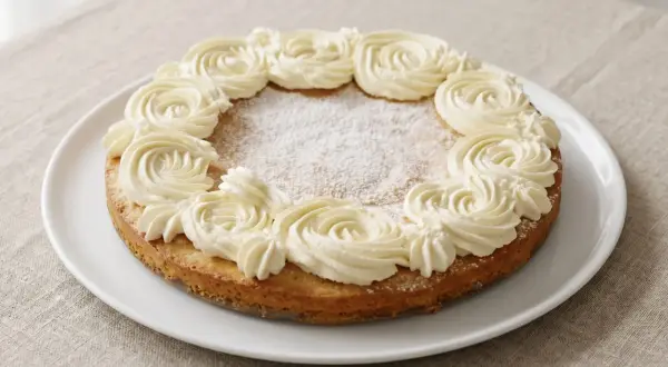 En glutenfri semmelkladdkaka med fluffig grädde runt kanten, pudrad med florsocker.