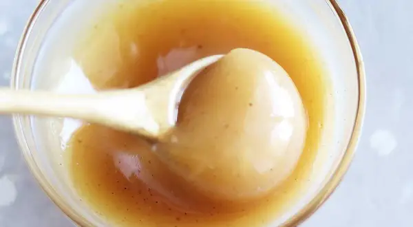 En sked lyfter krämig kolasås ur en skål. Perfekt för ditt kolasås recept!